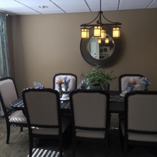 A well-decorated dining room featuring a stylish chandelier, elegant table settings, and a touch of greenery.