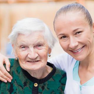 An elderly woman and a younger woman smiling together, showcasing warmth and togetherness.