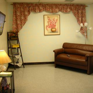 A cozy living room with a brown sofa, a decorative lamp, and a painting on the wall.