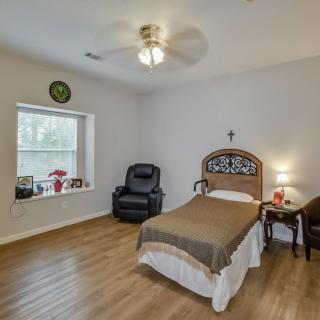 A cozy bedroom with a single bed, armchair, and wooden flooring.