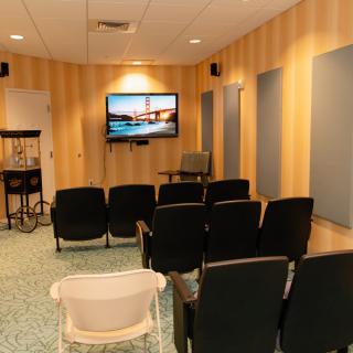 A cozy home theater room with multiple chairs facing a large screen on the wall.