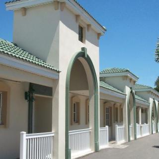 A building with arched entrances and a tiled roof, featuring an exterior arcade design.