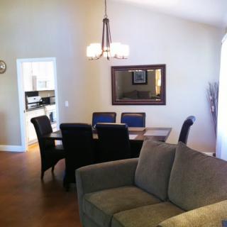 A cozy living and dining area featuring a modern sofa, dining table with chairs, and a decorative chandelier.