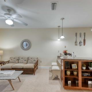 A cozy living space featuring a sofa, coffee table, and a bar area with hanging utensils and pendant lighting.