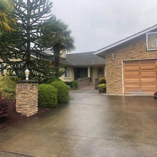 A scenic view of a house featuring a manicured garden and a welcoming driveway, captured on a rainy day.