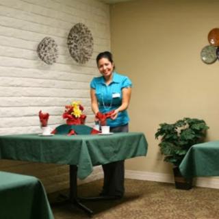 A staff member arranging flowers on tables in a restaurant setting.