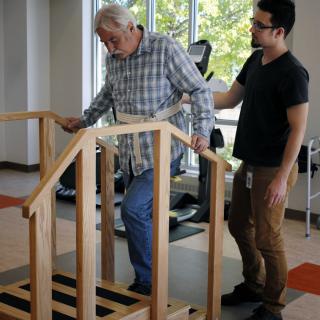 An elderly man receives assistance during a physical therapy session.