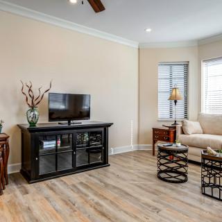 A cozy living room with a minimalist setup, featuring a TV on a black stand, a comfortable sofa, and wooden floors.