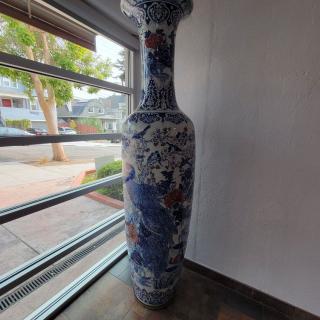 A large decorative blue and white ceramic vase with a floral design stands near a window.