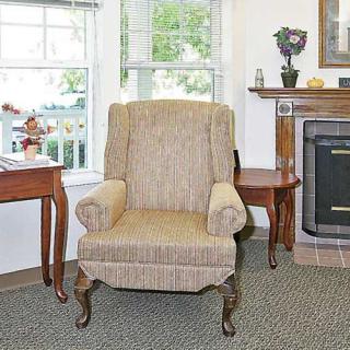 A cozy living room with an upholstered chair, side table, and fireplace.