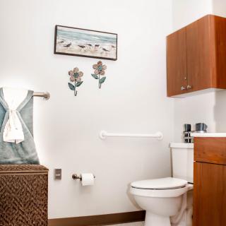 A neatly organized bathroom with a toilet, towels, and wall decor.