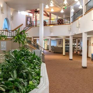 Spacious lobby interior with plants, stairs, and a balcony.