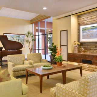 A welcoming and cozy living room featuring comfortable seating, a piano, and decorative plants.