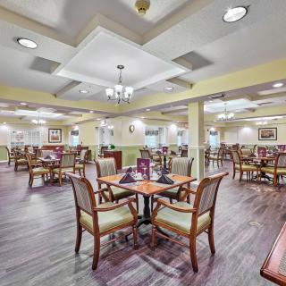 A spacious and elegantly designed dining room with neatly arranged tables and chairs, featuring warm lighting.