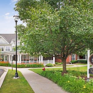A picturesque residential building surrounded by lush greenery and a well-maintained sidewalk.