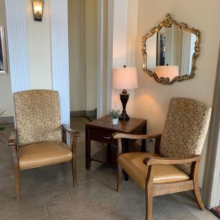 A cozy seating area with two armchairs, a small table with a lamp, and an ornate mirror on the wall.