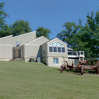 A modern house with large windows and a surrounding lawn on a sunny day.