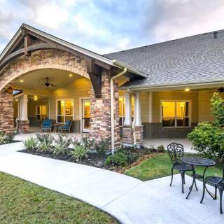 A beautiful house exterior featuring a landscaped path leading to a cozy patio with outdoor seating.