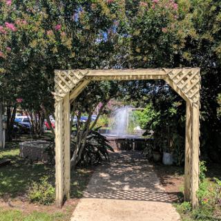 A charming garden archway leading to a serene area surrounded by lush greenery.