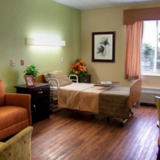 A hospital room with a patient bed, comfortable seating, and tasteful decor.