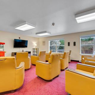 A cozy room with several armchairs, a television, and a popcorn machine on the bright red carpet.