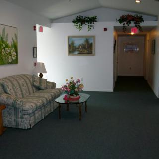 A cozy lobby area with a sofa, artwork, and decorative plants.