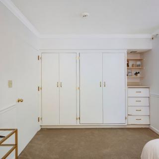 A bedroom with a white wardrobe and carpeted floor.