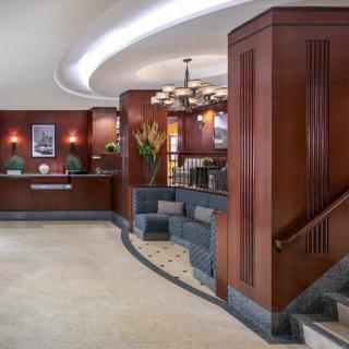 A stylish hotel lobby featuring art deco design elements with a reception desk, seating area, and elegant lighting.