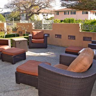 A cozy outdoor seating area with wicker furniture and orange cushions on a sunny patio.