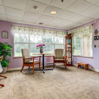 A cozy living space with purple walls and ample natural light, featuring comfortable rockers and decorative elements.
