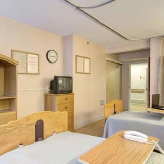 A hospital room with two patient beds and a television.
