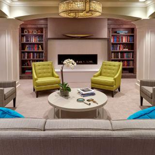 A cozy and modern living room with a central fireplace, stylish seating, and bookshelves lining the walls.