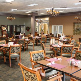 An elegantly decorated dining room with multiple tables and chairs, featuring chandeliers and a cozy atmosphere.