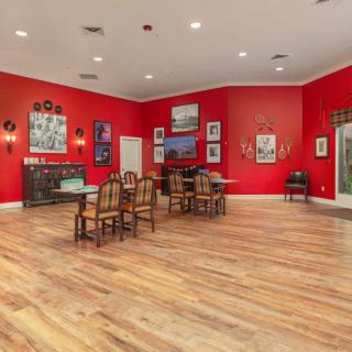 A spacious dining room with vibrant red walls, adorned with various artworks and wooden flooring.