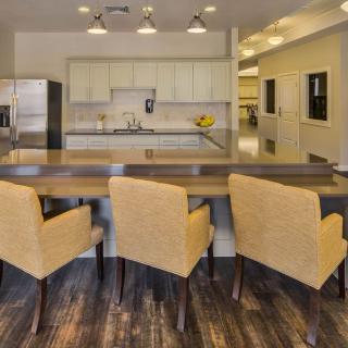 A modern kitchen with a large countertop and bar stools, featuring sleek appliances and open space design.