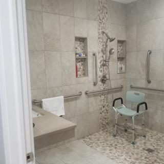 A modern, accessible bathroom with a walk-in shower and shower chair.