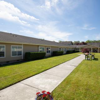 A single-story building with a well-maintained lawn and a sidewalk on a sunny day.
