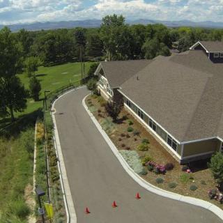 Aerial view of a building with a surrounding road and landscaped greenery.