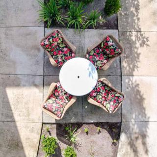 Aerial view of a patio with a round table and four chairs featuring floral cushions, surrounded by plants.