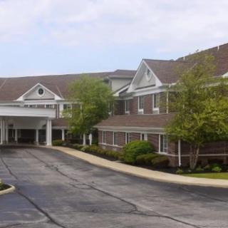 A large building with a covered entrance and surrounding greenery.