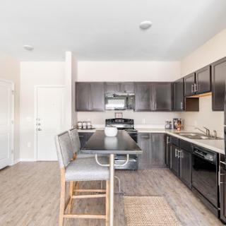 A sleek and modern kitchen featuring dark cabinets, stainless steel appliances, and a stylish bar seating area.