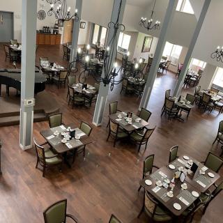 An elegant dining room with neatly arranged tables and a grand piano.