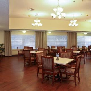 A spacious dining room with multiple tables and chairs, illuminated by elegant ceiling lights.