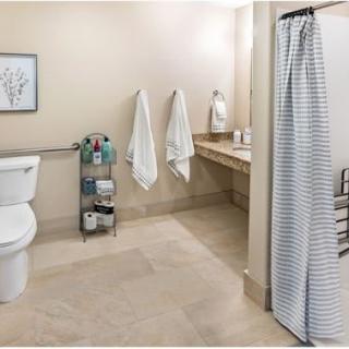 A clean and organized bathroom with a shower, toilet, sink, and storage rack.