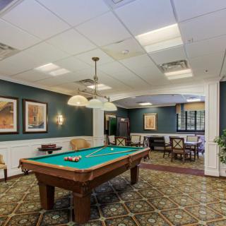 A cozy recreation room featuring a billiards table, ambient lighting, and seating areas.
