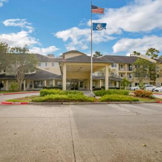 A large building with two flags, surrounded by landscaping under a partly cloudy sky.