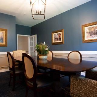 A stylish dining room with blue walls, featuring a wooden table, upholstered chairs, and framed artwork on the walls.