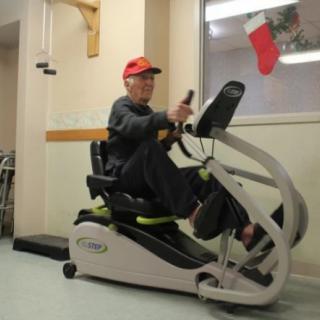 A senior person exercises on a recumbent bike indoors, focusing on health and wellness.