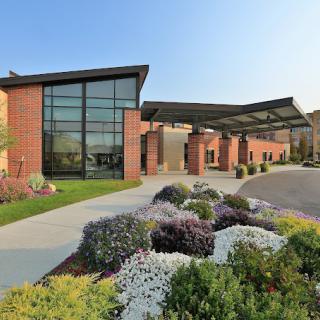 A modern building with large glass windows and well-maintained landscaping at the entrance.