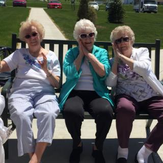 Three elderly women sitting on a bench enjoying a sunny day together.